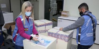 funcionários de colete e máscara separam 379 mil doses da vacina contra a Covid-19 chegaram a Santa Catarina