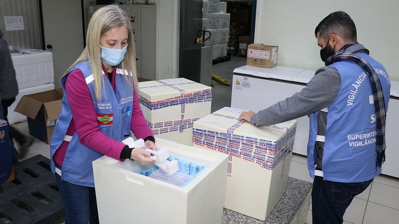 funcionários de colete e máscara separam 379 mil doses da vacina contra a Covid-19 chegaram a Santa Catarina