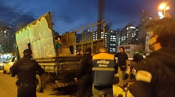 A foto mostra um caminhão de reciclagem parado com equipes da prefeitura em volta. A coleta clandestina desses caminhões recolhem os recicláveis antes da Comcap, comprometendo a renda e trabalho de coletores associados.