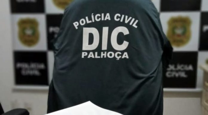 documento do inquérito com centenas de páginas sobre mesa com logo da dic e polícia civil ao fundo -