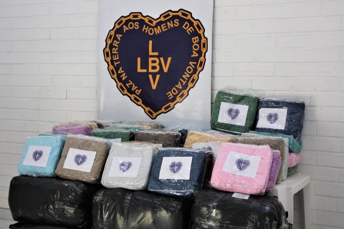 Cobertores coloridos e embalados aparecem enfileirados e acima um coração identifica a LBV. Os cobertores serão doados ao centro pop de são josé