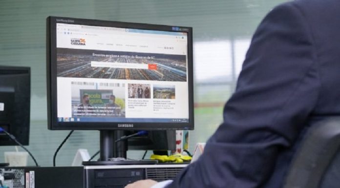 Governo de SC encaminha projeto para regulamentar home office A foto mostra uma mesa de trabalho com um computador ligado e uma pessoa a sua frente. O governo de SC encaminhou à Alesc um projeto de lei para regulamentar o home office para servidores do estado.