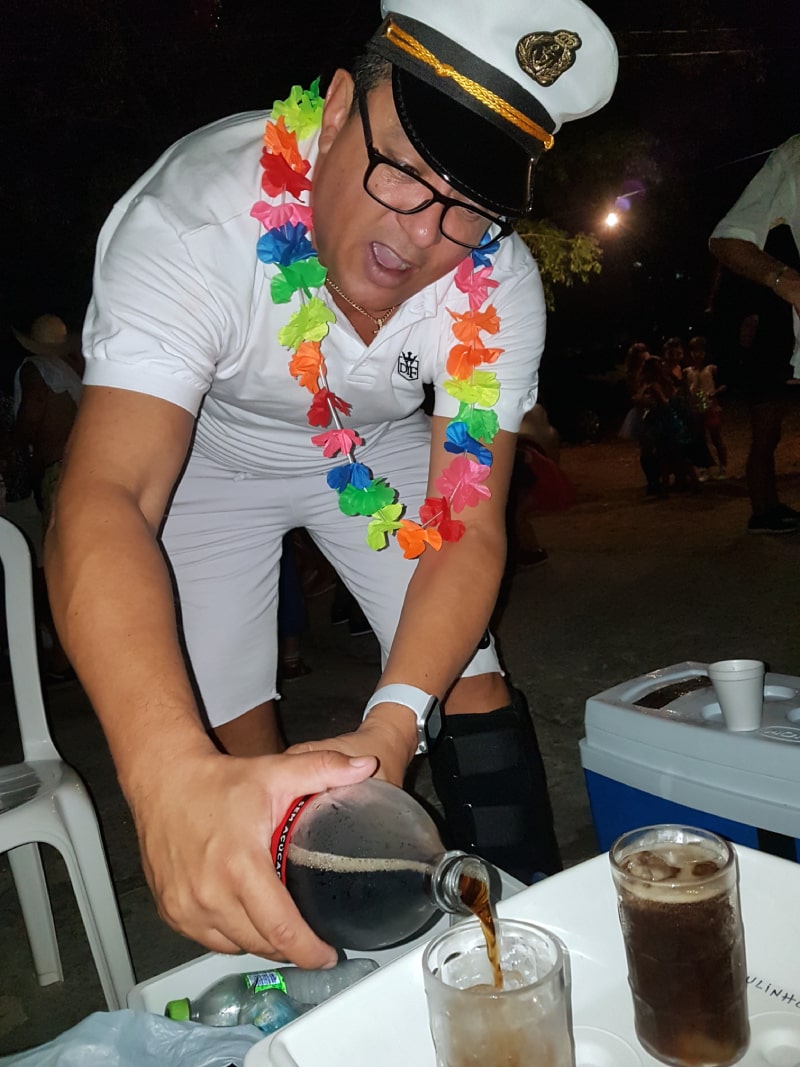 paulinho usando trajes de carnaval coloca coca-cola em bebida sobre mesa