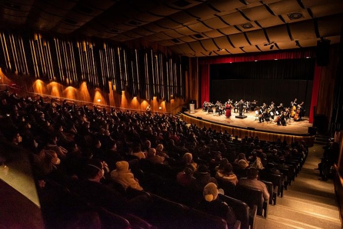 Primeiro evento-teste com público imunizado recebe cerca de 500 pessoas em SC - auditório lotado com orquestra cameratta no palco à frente