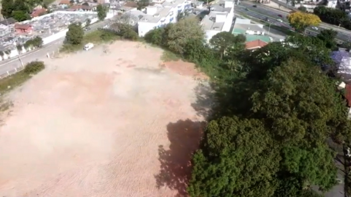 Vista de cima mostra um terreno vazio em Florianópolis com árvores em volta. A Udesc construirá no local o novo Cefid, além de uma escola estadual, no momento o projeto está restaurando o muro.