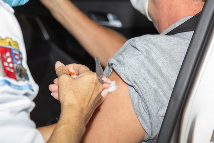 profissional de saúde aplica injeção no braço de homem dentro de carro - grande florianópolis avança na vacinação