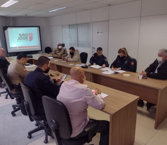 Em duas mesas separadas, sentados frente a frente, o secretário de segurança e representantes do comércio e forças de São José discutem o plano de metas para segurança de São José, que conta com ampliação do videomonitoramento em São José