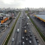 Foto de cima mostra as pistas com movimentação de carros e nas laterais prédios. A Arteris liberou 5 km da nova terceira faixa em trecho em São José.