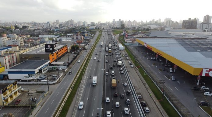 Foto de cima mostra as pistas com movimentação de carros e nas laterais prédios. A Arteris liberou 5 km da nova terceira faixa em trecho em São José.