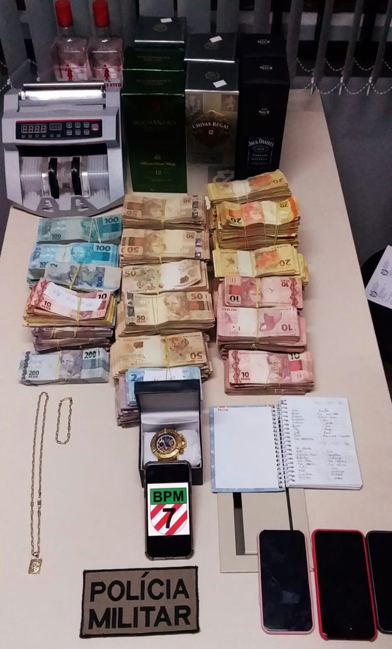 notas de dinheiro e outros objetos organizados sobre mesa - Polícia apreende R$ 347 mil do tráfico em kitnet em São José