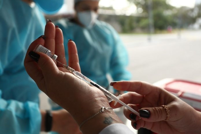 profissional retira dose de vacina de ampola com setinga - são josé e florianópolis vacinação população acima de 18 anos contra covid