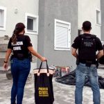 dois agentes da pc de costas em frente a prédio na deflagração da operação entulho contra construtores e agentes corruptos e obras irregulares em florianópolis