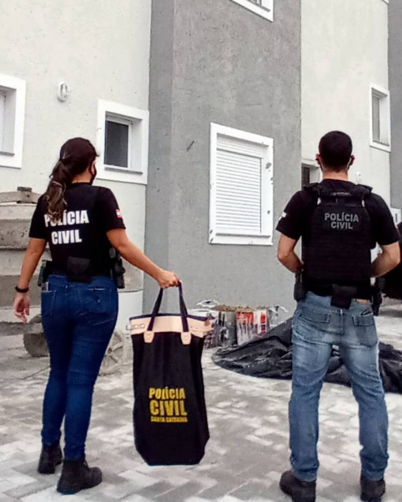 dois agentes da pc de costas em frente a prédio na deflagração da operação entulho contra construtores e agentes corruptos e obras irregulares em florianópolis