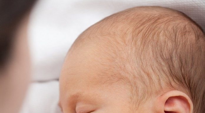Um bebê aparece de olhos fechados mamando. A campanha Agosto Dourado promove a amamentação e a importância do aleitamento materno.