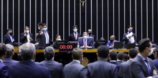 Deputados sentados no plenário de frente para outros deputados, que aparecem de costas na foto, todos vestem ternos. Os deputados aprovaram o texto base da reforma eleitoral, que entre alguns pontos votou o distritão e as coligações.