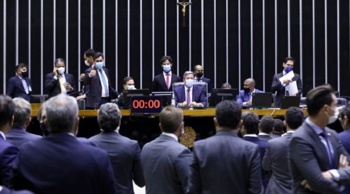 Deputados sentados no plenário de frente para outros deputados, que aparecem de costas na foto, todos vestem ternos. Os deputados aprovaram o texto base da reforma eleitoral, que entre alguns pontos votou o distritão e as coligações.