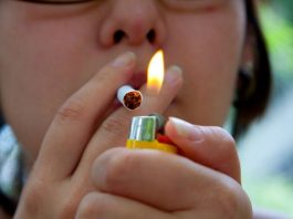 A foto foca na chama de um isqueiro acendendo um cigarro, que está na boca e preso aos dedos de uma pessoa. A imagem ilustra a notícia de que 51% dos cigarros consumidos em Santa Catarina em 2020 eram ilegais, contrabandeados ou de empresas nacionais devedoras.