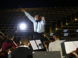 maestro rege orquestra sinfônica de santa catarina e ao fundo auditório vazio