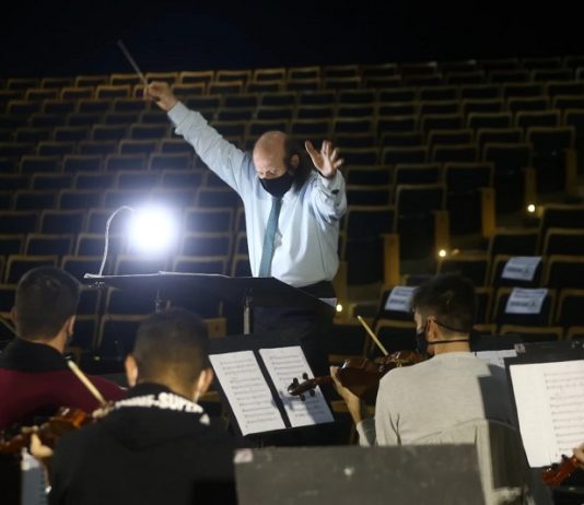 maestro rege orquestra sinfônica de santa catarina e ao fundo auditório vazio