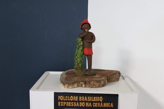 Um saci perere em cerâmica aparece no centro da foto e abaixo está escrito? Folclore Brasileiro Expressado na Cerâmica, nome da exposição aberta no museu histórico de são josé.