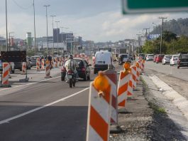 moto acessa marginal da br-101 atrás de fluxo de veículos com sinalização emergencial ao redoro