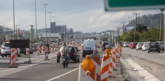 moto acessa marginal da br-101 atrás de fluxo de veículos com sinalização emergencial ao redoro