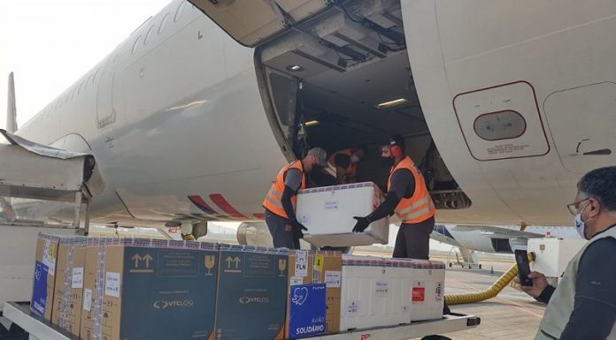 Dois homens de colete laranja retiram caixas de um avião. Nesta segunda, SC recebe mais de 250 mil doses de vacinas contra a covid.