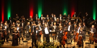 No palco, os músicos da orquestra sinfônica de sc (ossca) vestem terno escuro com camiseta branca e estão próximos aos seus instrumentos. A orquestra retorna aos palcos com o concerto beethoven 250, em são josé.