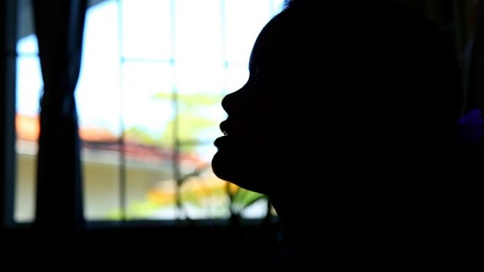 Uma janela ao fundo borrada na foto e o contorno de um rosto que aparece totalmente escuro pela foto. A prefeitura de Florianópolis criou o benefício desacolhimento, para mulheres vítimas de violência e jovens em casas de passagem.
