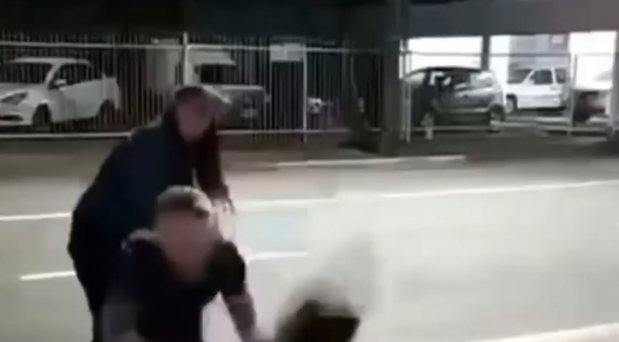 Frame de um vídeo que mostra as agressões de um homem contra outro homem. Na imagem, a vítima é jogada no chão pelo agressor, enquanto uma mulher observa e tenta se aproximar. O caso é tratado como suspeita de homofobia e ocorreu em Jaraguá do Sul.