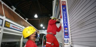homens instalam sistema de prevenção de incêndio no mercado público de florianópolis ao lado de peixarias fechadas