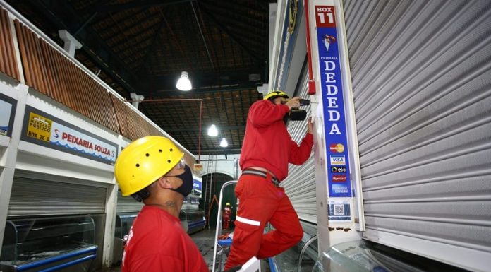 homens instalam sistema de prevenção de incêndio no mercado público de florianópolis ao lado de peixarias fechadas