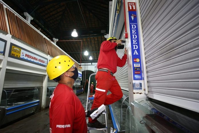 homens instalam sistema de prevenção de incêndio no mercado público de florianópolis ao lado de peixarias fechadas