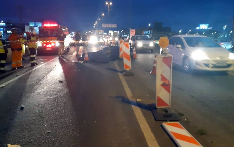 sinalização da rodovia com equipes de emergência ao fundo e carros passando ao lado - Duas pessoas morrem em acidente de moto na BR-101 em Palhoça