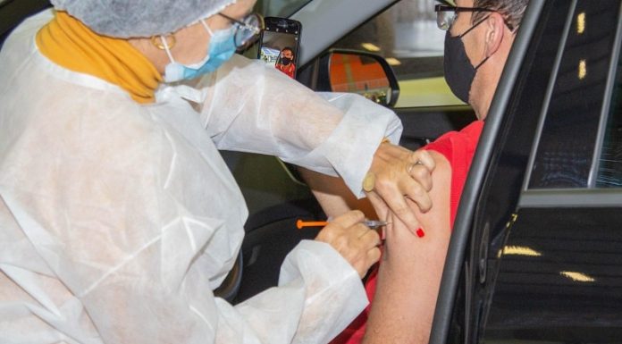 reforço de vacinação contra covid-19 coronavírus - homem recebe dose no braço sentado no carro