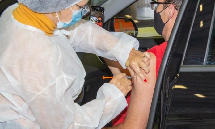 reforço de vacinação contra covid-19 coronavírus - homem recebe dose no braço sentado no carro