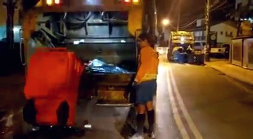 duas equipes de coleta de lixo na mesma rua em florianópolis, uma da comcap, outra da terceirizada, ao fundo