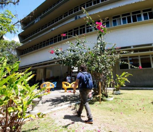 aluno anda por gramado com flores em volta e em frente a um prédio - calendário de retorno das aulas presenciais na udesc, ufsc e ifsc