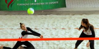 duas jogadores de vôlei de praia do mesmo lado da quadra de areia indoor