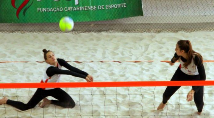 duas jogadores de vôlei de praia do mesmo lado da quadra de areia indoor