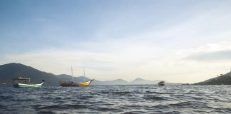 barcos na lagoa da conceição, em florianópolis, com montanhas ao fundo