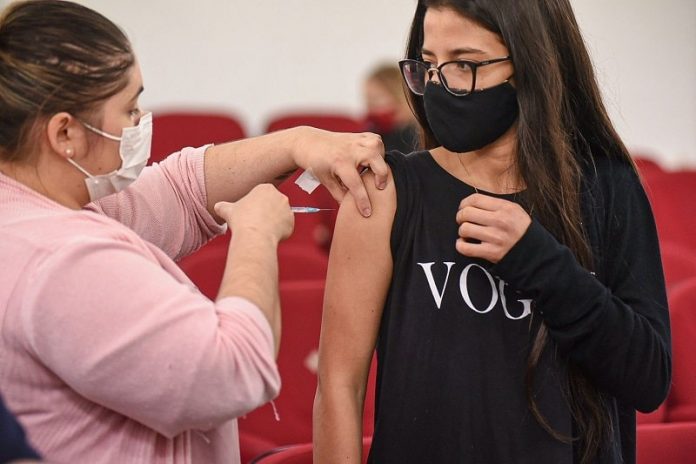 garota recebe vacina no braço olhando para enfermeira