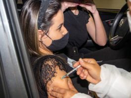 moça é vacinada no braço; ela olha pra frente, usando máscara, sentada no banco do carona - vacinação de adolescentes na grande florianópolis