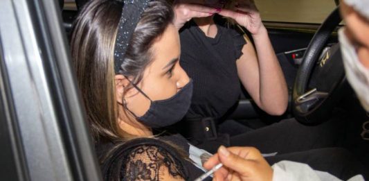 São José, Florianópolis e Biguaçu iniciam vacinação de adolescentes; Palhoça vacina 18+ moça é vacinada no braço; ela olha pra frente, usando máscara, sentada no banco do carona - vacinação de adolescentes na grande florianópolis