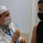 enfermeira mostra seringa de vacina para adolescente - população total vacinada imunizada na grande florianópolis