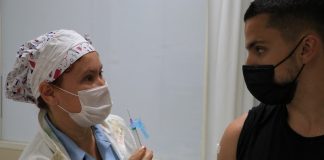 enfermeira mostra seringa de vacina para adolescente - população total vacinada imunizada na grande florianópolis