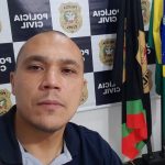 Delegado Manoel Galeno assume delegacia regional de São José - galeno em foto na frente de painel da polícia civil e bandeiras