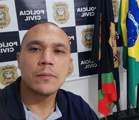 Delegado Manoel Galeno assume delegacia regional de São José - galeno em foto na frente de painel da polícia civil e bandeiras