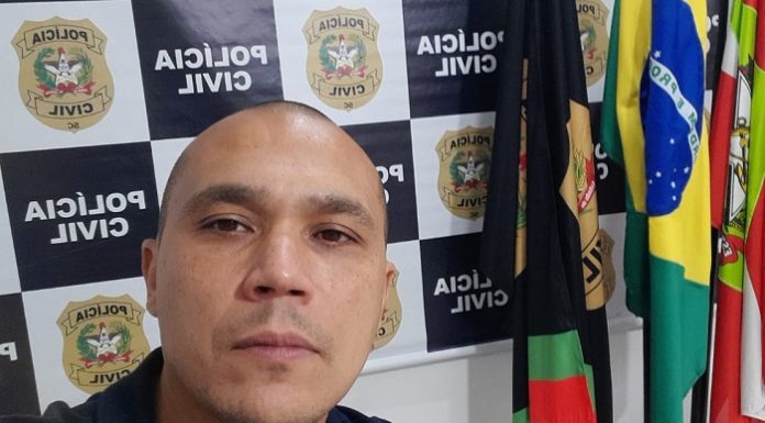 Delegado Manoel Galeno assume delegacia regional de São José - galeno em foto na frente de painel da polícia civil e bandeiras