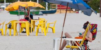 pessoas sentadas em cadeiras na praia - itapema proíbe caixas de som na praia